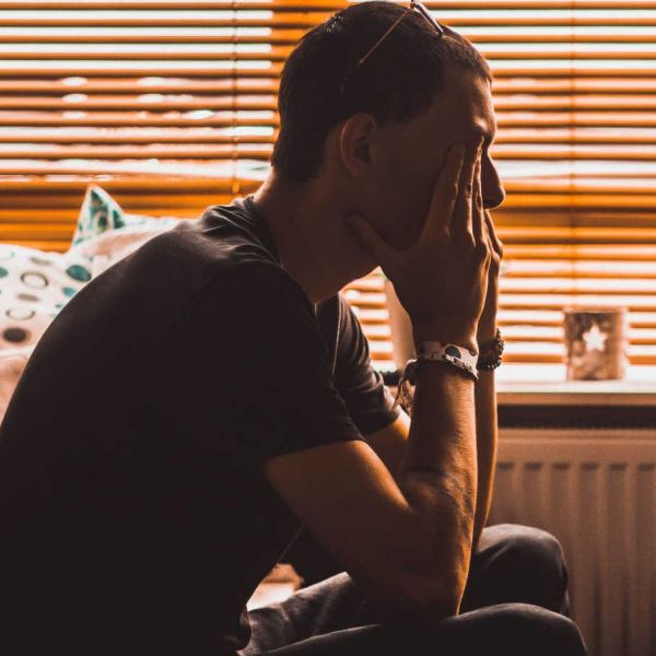 man sits in a dark room struggling with mental health conditions