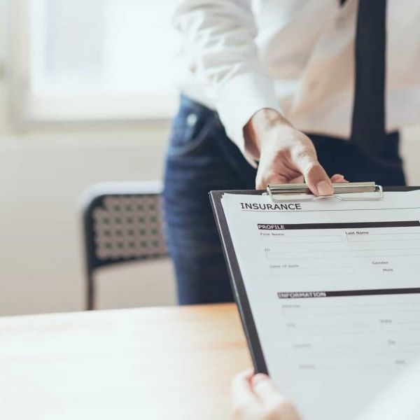 admissions specialist hands new client a health insurance form