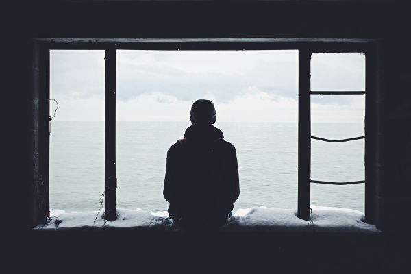 a young man looks out of a window struggling with mental health