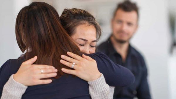 two women hug has they struggle with mental health issues