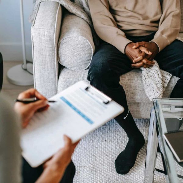 a man sits in a therapy session with a therapist who is treating him for mental health issues