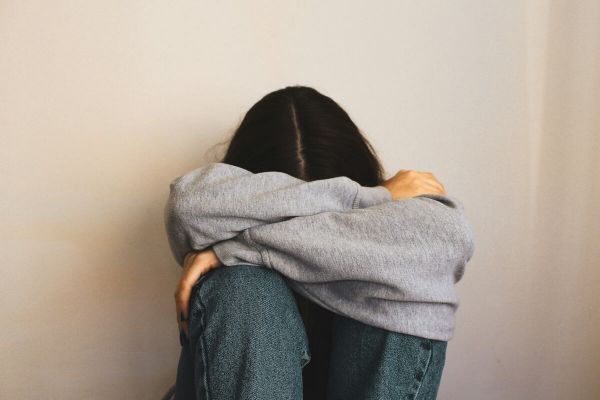 Young girl has her head in her knees as she struggles with mental health