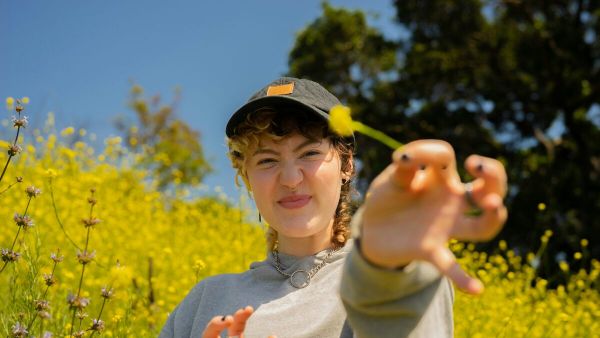 Young woman stands in the a field of flowers representing mental health treatment