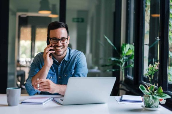 man is on the phone in front of a computer researching mental health recovery services.