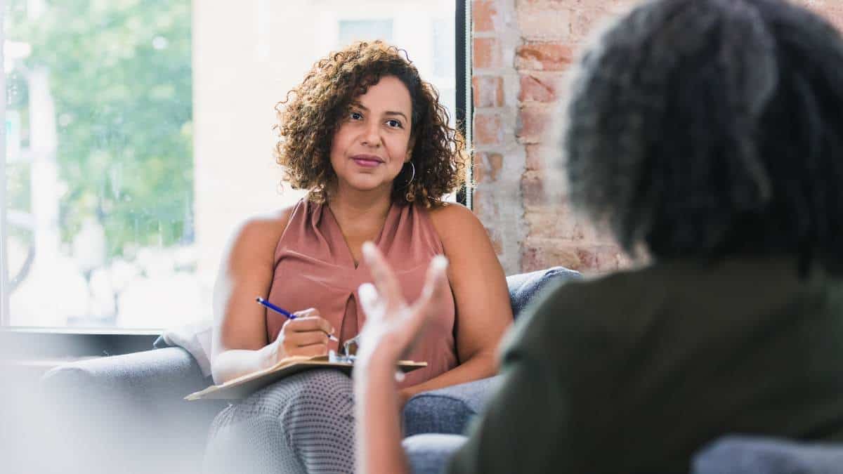 Female therapist actively listening to a patient in an individual therapy session, demonstrating how to help someone struggling with mental health.