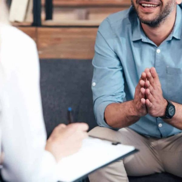 a man sits in a therapy session with a therapist who is treating him for mental health issues