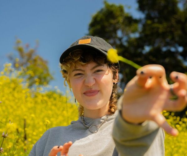 Young woman stands in the a field of flowers representing mental health treatment