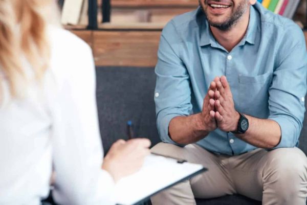 a man sits in a therapy session with a therapist who is treating him for mental health issues