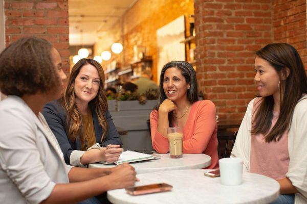 A group of woman out to dinner together discussing the benefits of mental health treatment