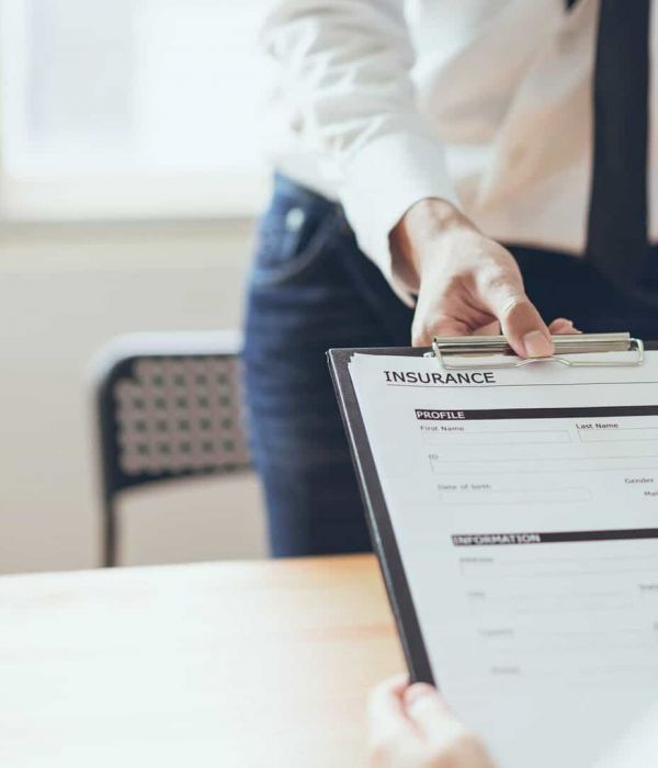 admissions specialist hands new client a health insurance form