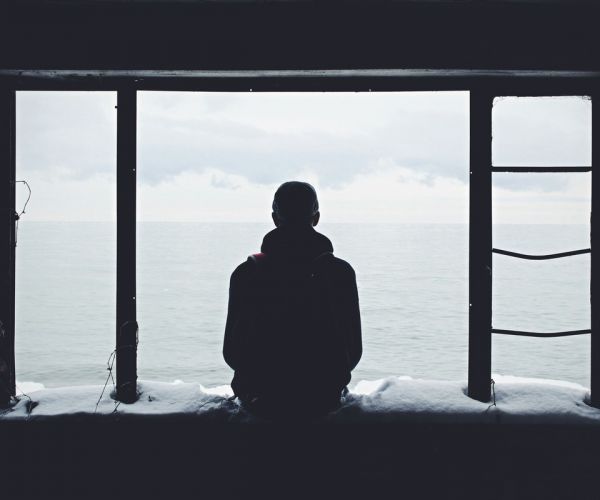 a young man looks out of a window struggling with mental health