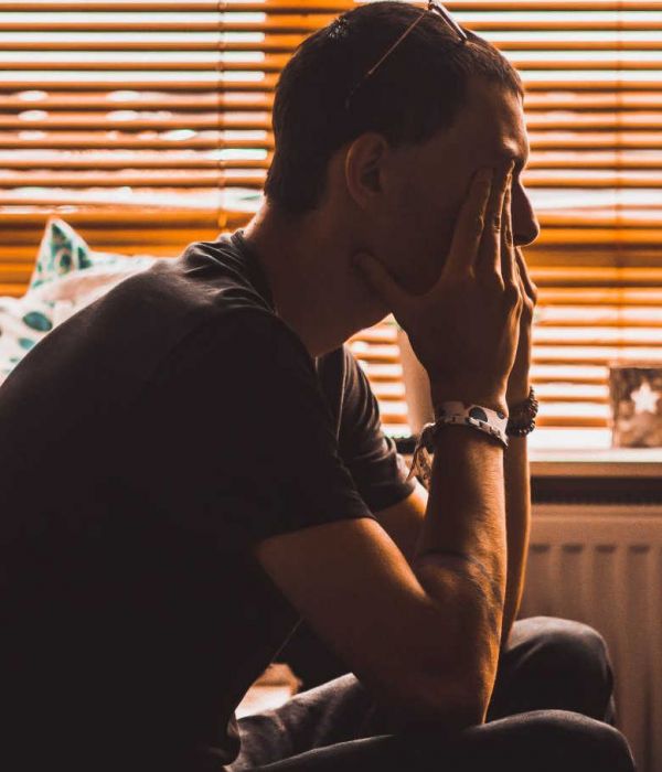 man sits in a dark room struggling with mental health conditions