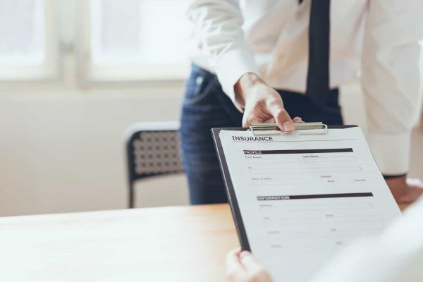 admissions specialist hands new client a health insurance form