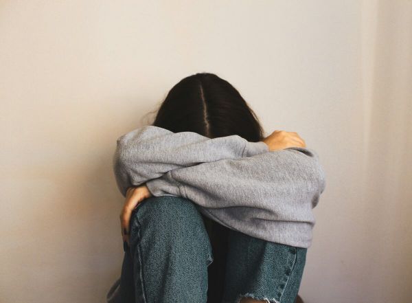 Young girl has her head in her knees as she struggles with mental health