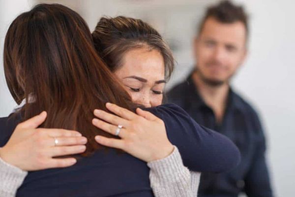 two women hug has they struggle with mental health issues