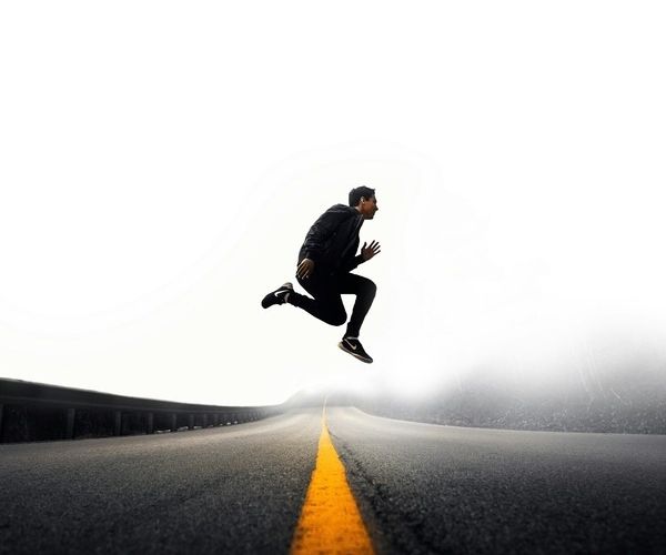 man jumping in the air across a road celebrating success over mental help