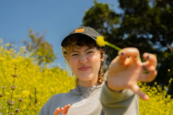 Young woman stands in the a field of flowers representing mental health treatment