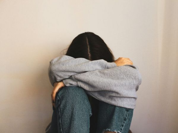 Young girl has her head in her knees as she struggles with mental health